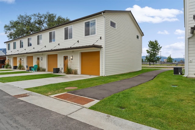 townhome / multi-family property with cooling unit, a garage, and a front lawn