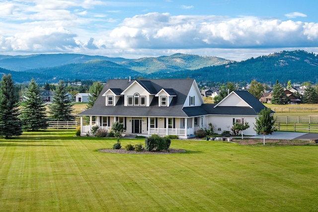 view of front of house with covered porch, a mountain view, and a front yard