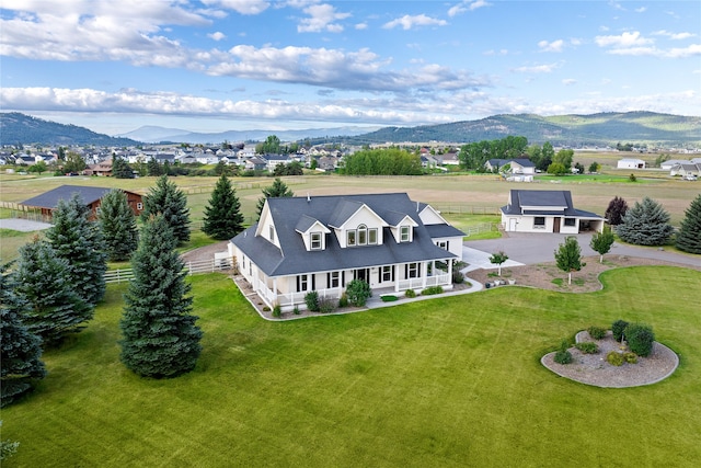 view of front of house with covered porch, a mountain view, and a front yard