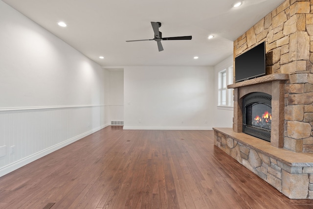 unfurnished living room featuring a fireplace, dark hardwood / wood-style floors, and ceiling fan