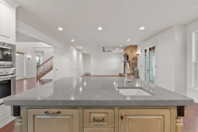 kitchen with an island with sink, appliances with stainless steel finishes, and hardwood / wood-style floors