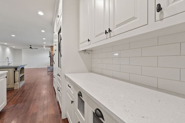 kitchen featuring light stone counters, dark hardwood / wood-style floors, sink, white cabinetry, and ceiling fan