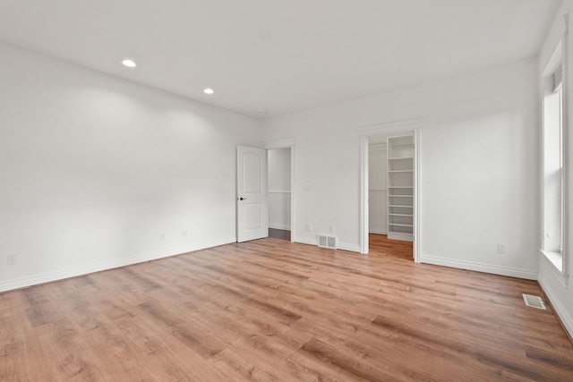 unfurnished bedroom with a closet, light hardwood / wood-style floors, and a spacious closet