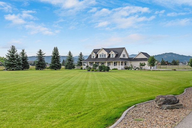 view of front of house featuring covered porch, a mountain view, and a front yard