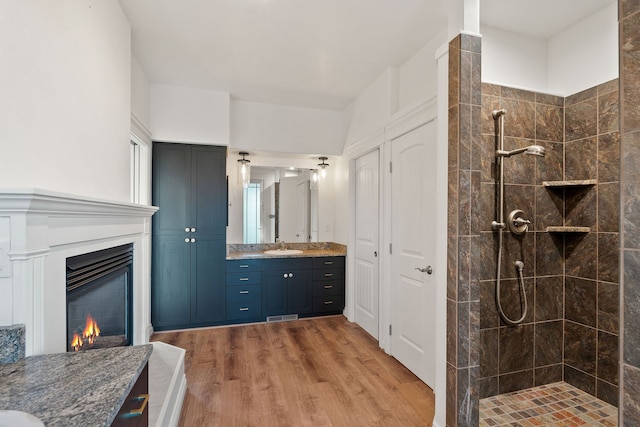 bathroom featuring hardwood / wood-style flooring, vanity, and tiled shower