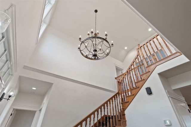 staircase with a towering ceiling and a chandelier