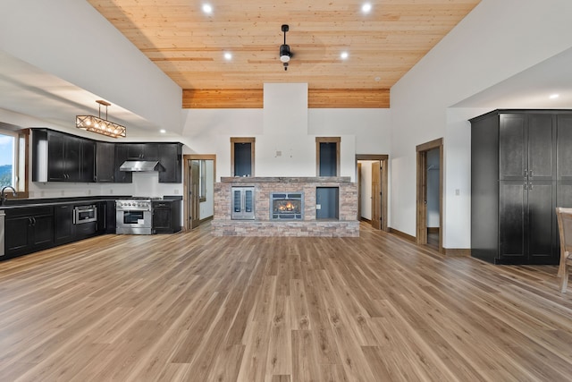 unfurnished living room with wood ceiling, sink, a fireplace, a towering ceiling, and light hardwood / wood-style floors