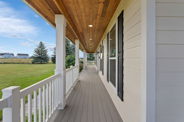 wooden terrace with covered porch and a yard