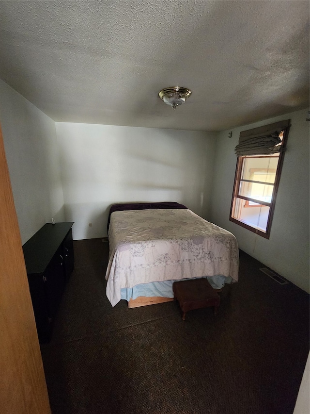 unfurnished bedroom featuring dark carpet and a textured ceiling