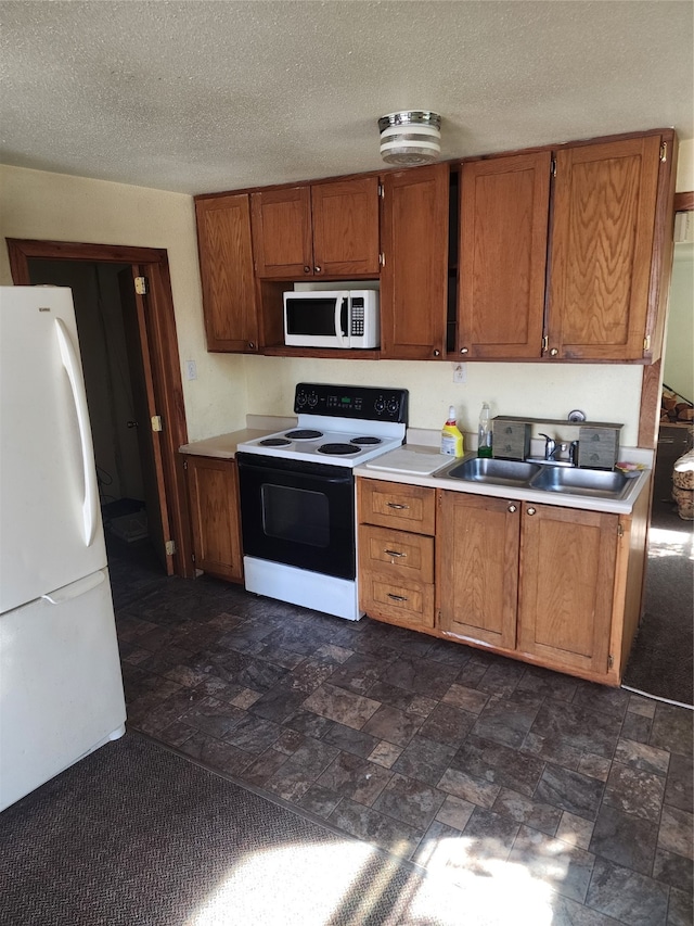 kitchen featuring white appliances, a textured ceiling, and sink