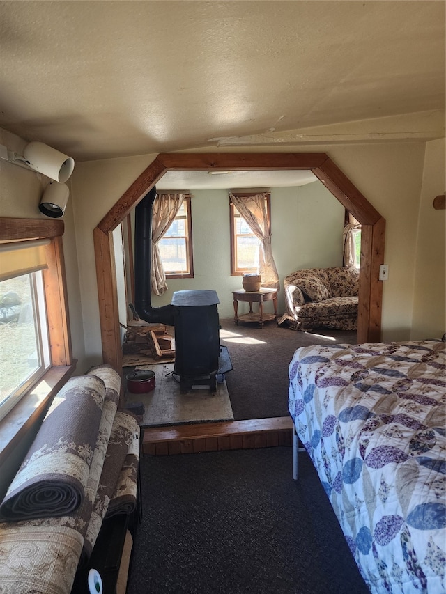 carpeted bedroom with a wood stove and a textured ceiling