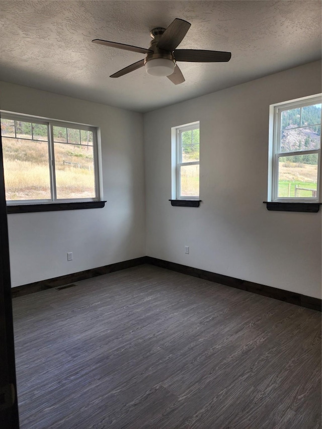 spare room featuring dark wood-type flooring, ceiling fan, and a textured ceiling