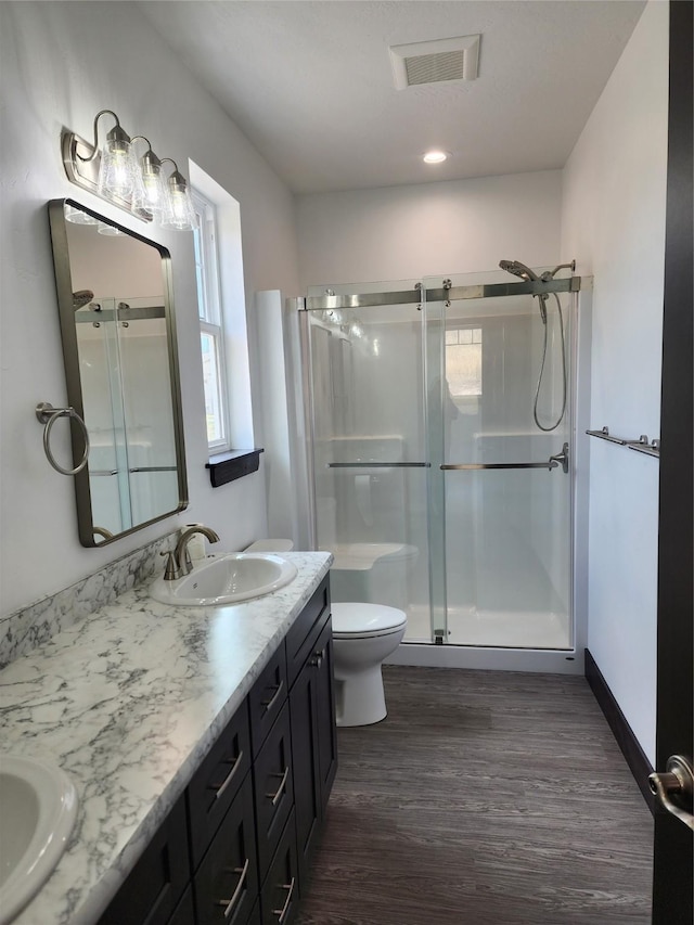 bathroom featuring an enclosed shower, vanity, hardwood / wood-style floors, and toilet