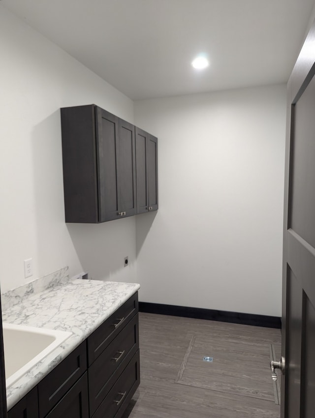 laundry room featuring cabinets, electric dryer hookup, dark hardwood / wood-style floors, and sink