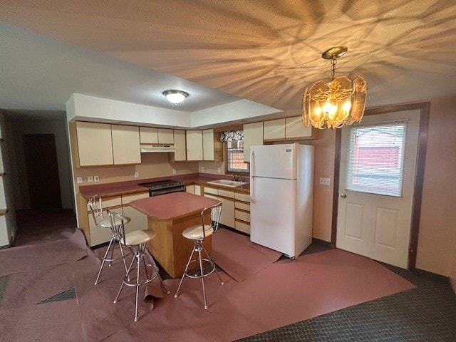 kitchen featuring carpet, a kitchen island, stainless steel range with electric cooktop, and white refrigerator