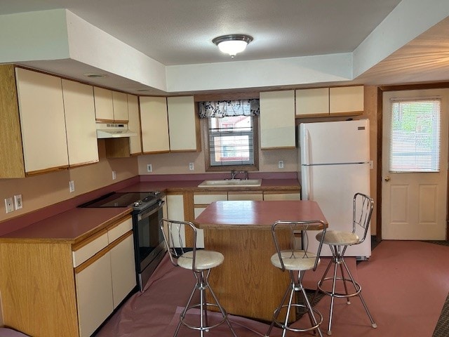 kitchen with a center island, sink, a kitchen bar, white fridge, and stainless steel range with electric stovetop