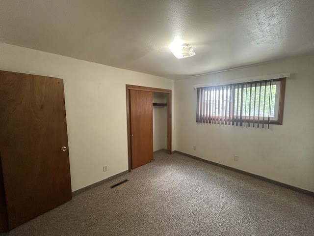 unfurnished bedroom featuring carpet, a closet, and a textured ceiling