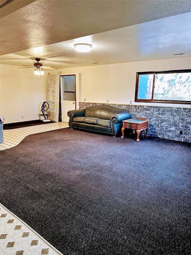 unfurnished living room with a textured ceiling, carpet floors, and ceiling fan