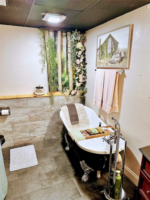 bathroom featuring a washtub, a drop ceiling, and vanity