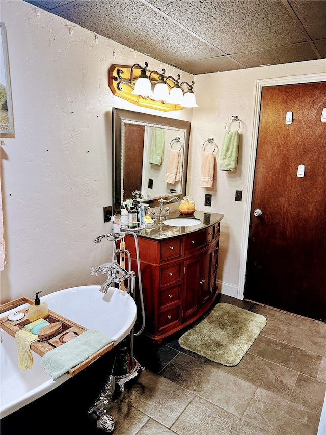 bathroom with a paneled ceiling, vanity, and a bath