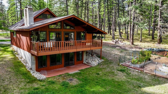 rear view of house featuring a lawn and a wooden deck