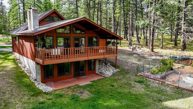 346 Crystal Lakes Dr, Eureka, MT 59917 - back of property with a vegetable garden, a lawn, a chimney, and a wooden deck