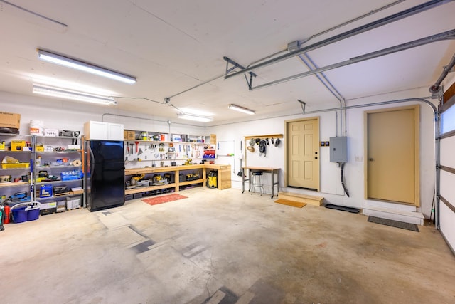 garage with a workshop area, electric panel, and black fridge