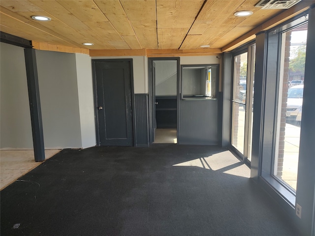 carpeted spare room with wood ceiling