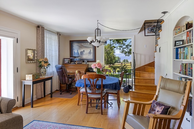 dining space with a notable chandelier, light wood-type flooring, and crown molding