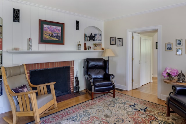 living area with light hardwood / wood-style floors, ornamental molding, and a brick fireplace