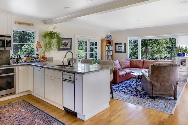 kitchen featuring white cabinets, sink, kitchen peninsula, stainless steel appliances, and light hardwood / wood-style floors