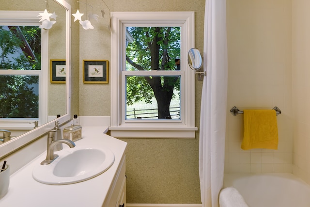 bathroom featuring vanity, a bath, and a healthy amount of sunlight