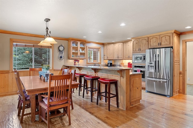 kitchen with a wealth of natural light, stainless steel appliances, kitchen peninsula, and light wood-type flooring