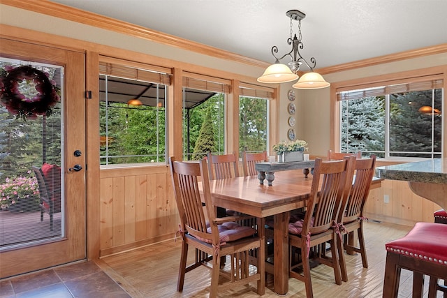 dining space with crown molding, wood walls, and a wealth of natural light