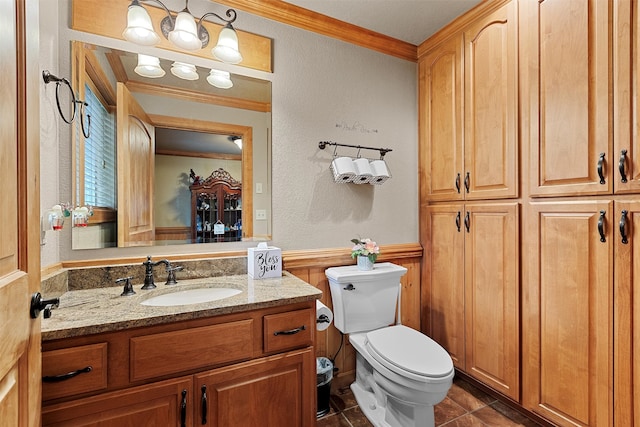 bathroom featuring tile patterned flooring, vanity, ornamental molding, and toilet