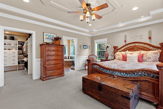 bedroom featuring crown molding, light colored carpet, connected bathroom, and a spacious closet