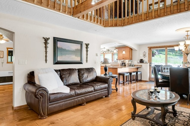 living room featuring a textured ceiling, light hardwood / wood-style floors, and a notable chandelier