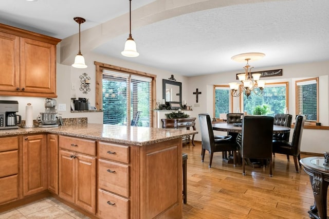 kitchen featuring light hardwood / wood-style flooring, kitchen peninsula, a notable chandelier, and pendant lighting