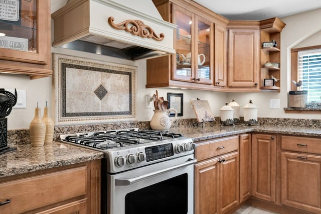 kitchen featuring dark stone countertops, stainless steel gas stove, and custom range hood