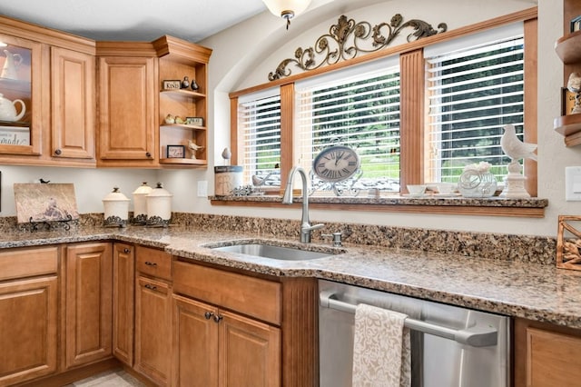 kitchen with light stone countertops, dishwasher, and sink