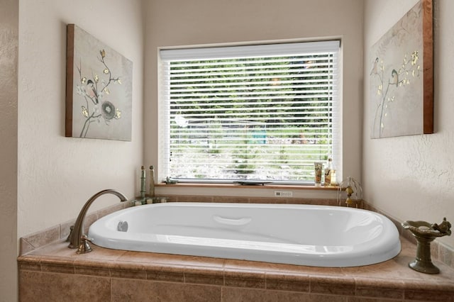 bathroom featuring a healthy amount of sunlight and tiled tub