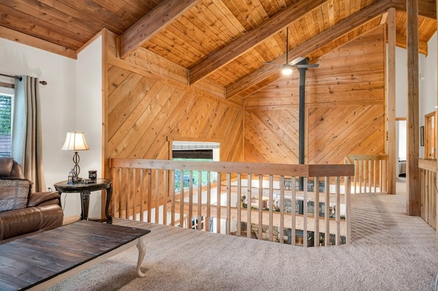 living area with high vaulted ceiling, beamed ceiling, wooden ceiling, carpet, and wooden walls