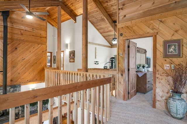 corridor featuring wood ceiling, beam ceiling, wooden walls, high vaulted ceiling, and light carpet