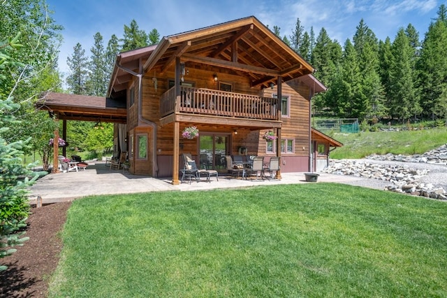 rear view of house with a balcony, a patio, and a lawn