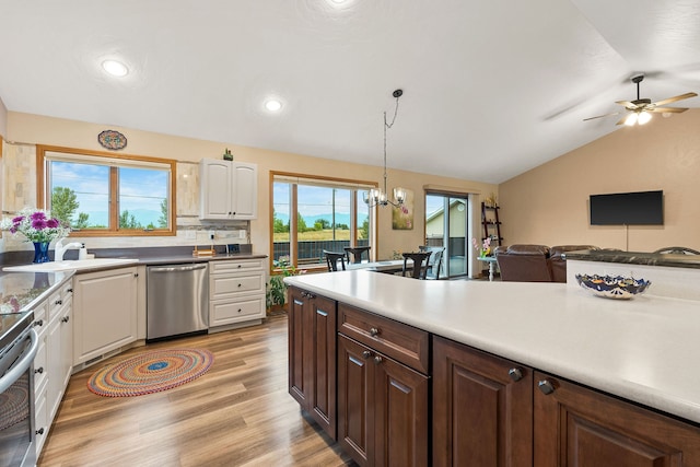 kitchen featuring light wood-type flooring, decorative light fixtures, appliances with stainless steel finishes, ceiling fan with notable chandelier, and vaulted ceiling