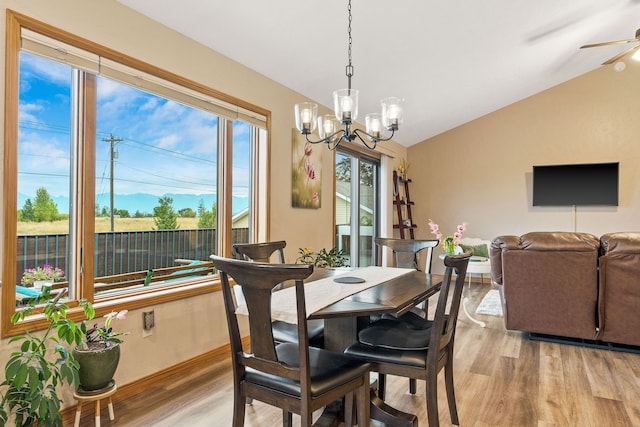 dining area with light hardwood / wood-style floors, ceiling fan with notable chandelier, and lofted ceiling