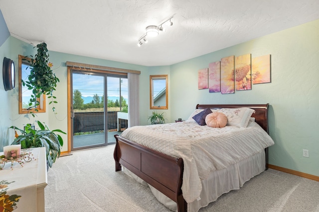 carpeted bedroom with access to outside, a textured ceiling, and track lighting