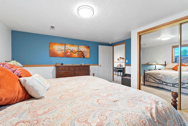 carpeted bedroom with a textured ceiling and a closet