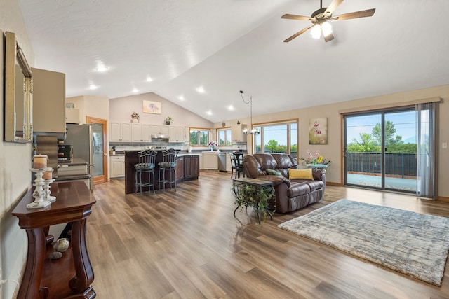 living room with vaulted ceiling, hardwood / wood-style floors, ceiling fan, and a wealth of natural light