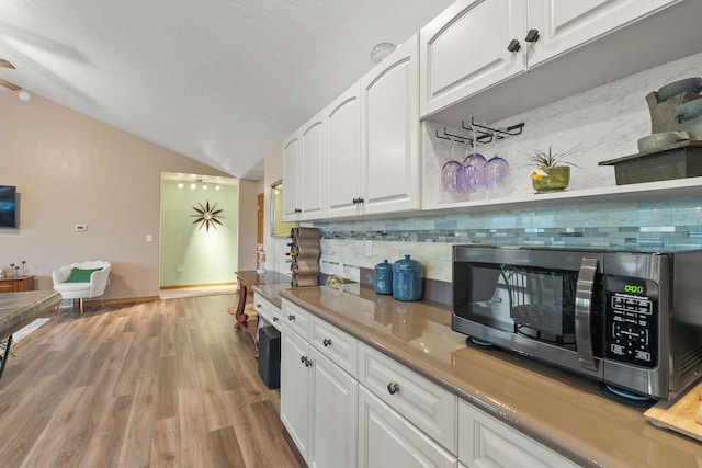 kitchen with light wood-type flooring, backsplash, and white cabinetry